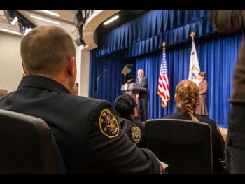 A view from the crowd at the Medal of Valor ceremony of a man standing on a stage and giving a speech from a podium.