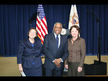 three people standing together in front of a stage and smiling at the camera